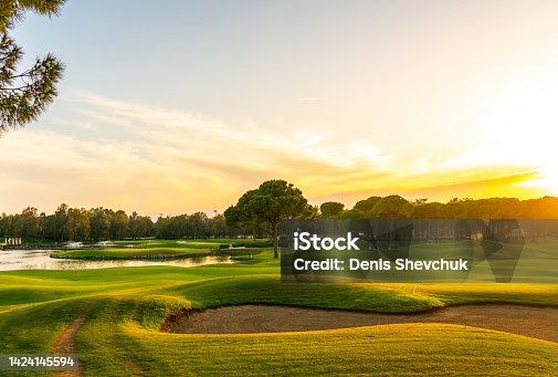 istock Panorama of the most beautiful sunset or sunrise. Sand bunker on a golf course without people with a row of trees in the background 1424145594