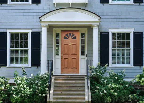 Front door of traditional two story suburban clapboard house with shutters