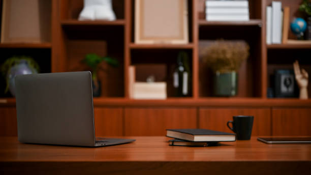 Modern classic vintage office workspace with laptop, coffee mug and books on wooden table. stock photo