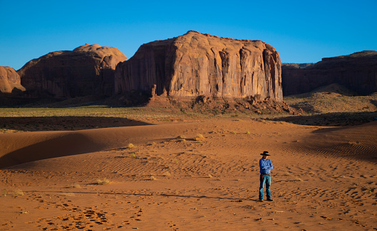 Navajo man on the sand dunes in Monument Valley at sunset