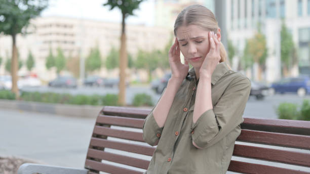 istock Distressed Woman with Headache Sitting Outdoor on Bench 1424160206
