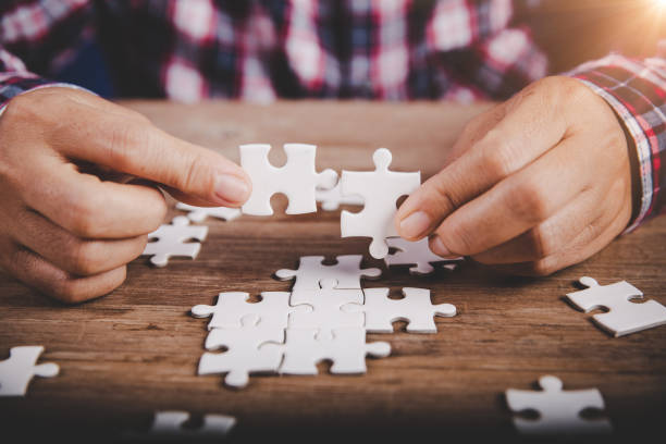 istock Hands holding jigsaw puzzles piece on wooden table background, success business, solution strategy, teamwork partnership concept 1424161244