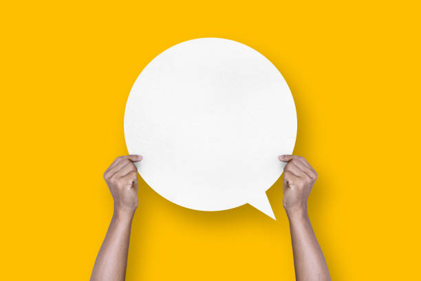 istock hand holding round white paper balloons speech bubbles isolated on yellow background 1424162001