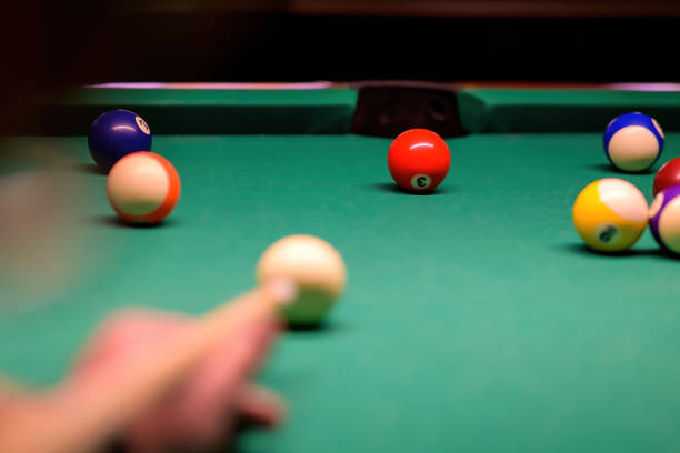 billiard balls in a green billiard table. blurred hand with cue pointing at billiard ball at table - snooker table imagens e fotografias de stock