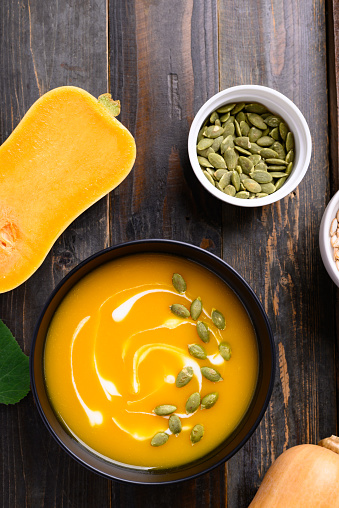 Butternut squash pumpkin soup in bowl on wooden background, Homemade food in autumn season, Table top view