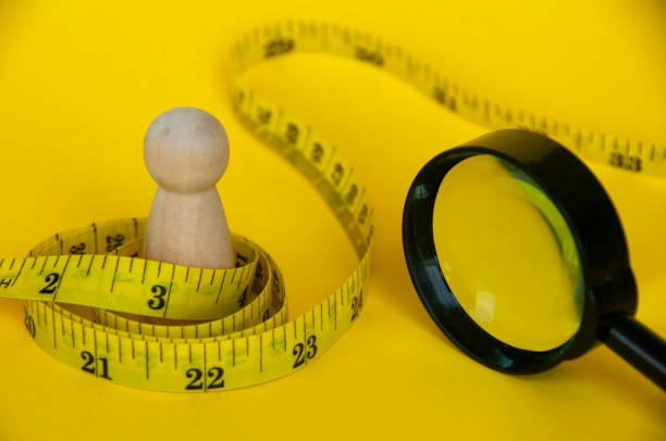 istock Wooden doll wrapped with yellow measuring tape with customizable space for text or ideas. Copy space and weight loss concept 1424165935