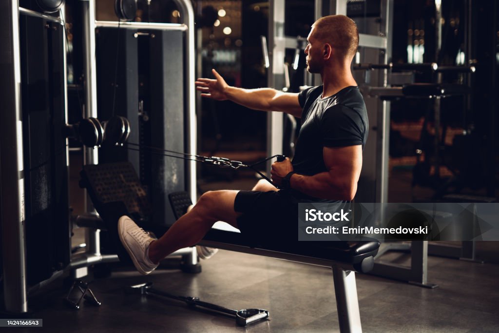 Man Straining As He Rows Muscular Man Doing Exercise In Seated Cable Row Machine Stock Photo ...