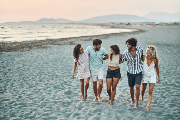 istock Young happy friends talking while walking embraced on the beach. 1424167665
