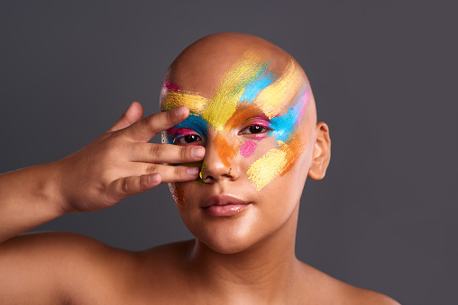 Face makeup, art paint and woman with creative cosmetics design, splash of color and body of artist against a grey mockup studio background. Portrait of girl model with rainbow drawing for beauty
