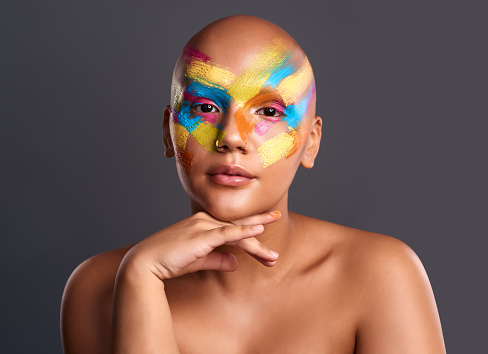 Woman, portrait and paintbrush makeup with studio background for copy space or mockup. Beautiful and young bald girl with creative, colorful and beauty art cosmetic face style and pose.