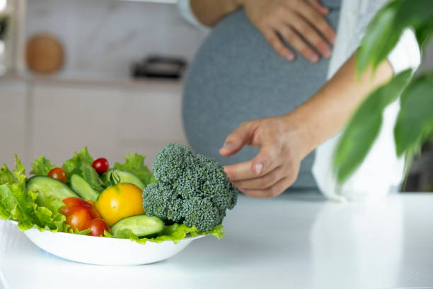 Pregnancy nutrition Pregnant woman stretch hand to plate with vegetables and fruits on table. Nutrition and healthy diet during pregnancy. Healthy eating full of vitamins and antioxidants for pregnant woman. gestational diabetes stock pictures, royalty-free photos & images
