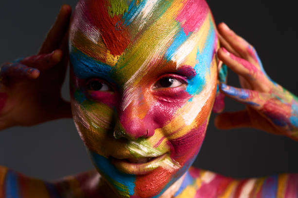 istock Model, bodypaint and art pose in studio background for creative and colorful mind of a creator. Abstract, artistic and fashion makeup paint on bald woman with edgy and contemporary style. 1424179091