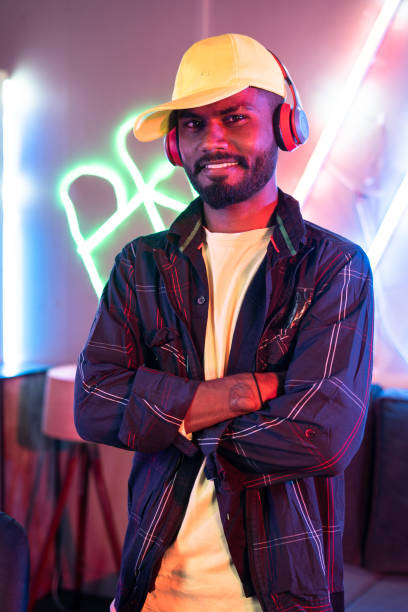 istock Confident professional gamer with headset standing by arms crossed while looking camera at home - concept of live steamer, tournament and champion. 1424180005