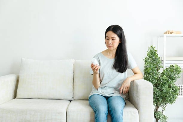 istock Woman looking at pill bottle label at home. 1424180870