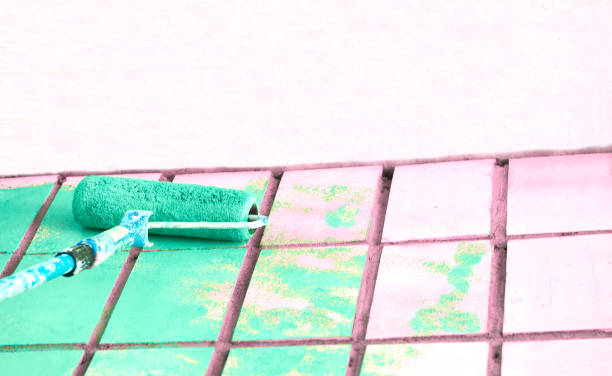 istock Roller painting pale pink wall surface with green emerald paint 1424182271