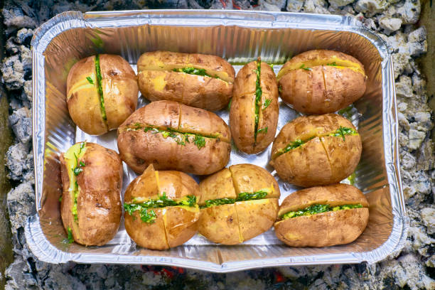 istock Baked potatoes with herbs, bacon and spices in a metal foil container 1424183192