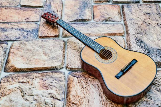 istock Acoustic yellow brown guitar on orange brick cobblestone surface 1424183201