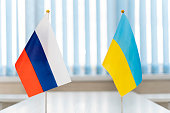 Close up Russian and Ukrainian flags. Diplomats negotiate on war between Russia and Ukraine. International relations. Conflict settlement negotiations. Diplomacy.