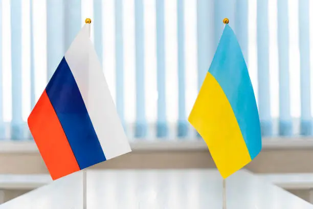 Photo of Close up Russian and Ukrainian flags. Diplomats negotiate on war between Russia and Ukraine. International relations. Conflict settlement negotiations. Diplomacy.