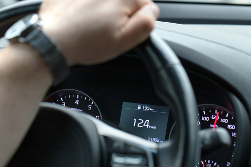 Close-up of car dashboard while driving. Speed of vehicle is 124 kilometers per hour. Shallow depth of field.