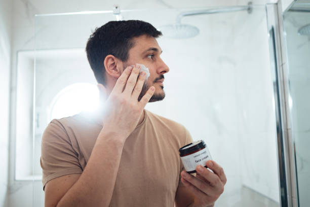 istock Handsome Man Applying Face Cream in the Bathroom (Copy Space) 1424187838