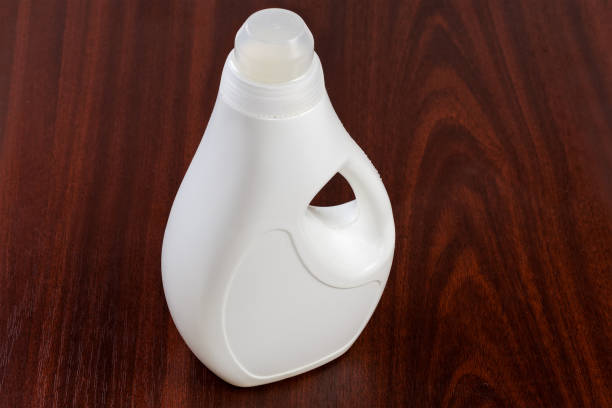 bottiglia di plastica di detersivo liquido per bucato su una superficie di legno - laundry detergent cleaning product concepts measuring cup foto e immagini stock