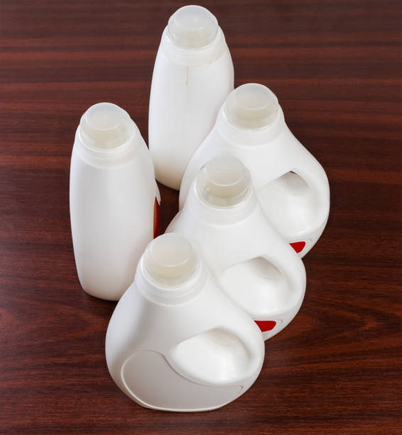 bottiglie di plastica di detersivo liquido per bucato su un tavolo di legno - laundry detergent cleaning product concepts measuring cup foto e immagini stock