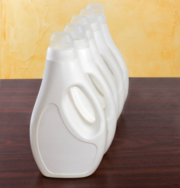 plastikflaschen mit flüssigem waschmittel auf einem holztisch - laundry detergent cleaning product concepts measuring cup stock-fotos und bilder