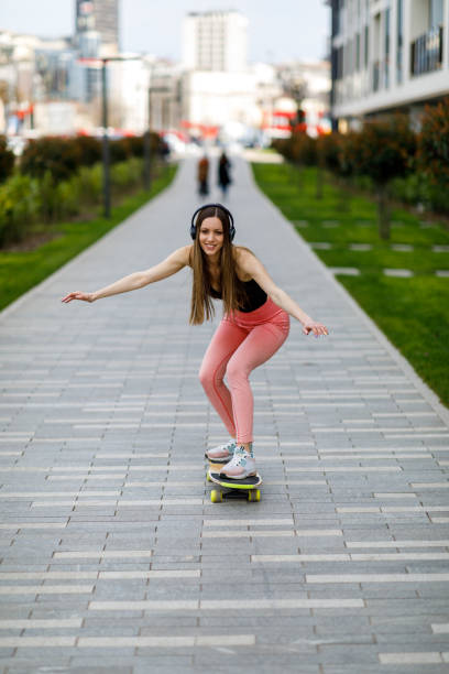 istock Beautiful Woman is Having Fun While Riding Skateboard in a Park. 1424190896