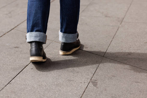 Woman's feet and legs as she walks away from the viewer on a sunny day.