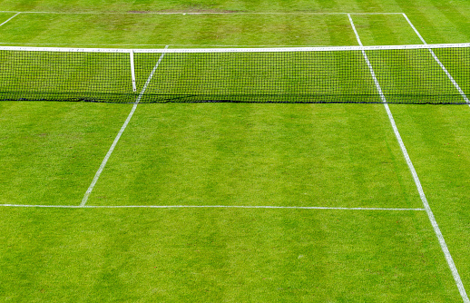 Woman in black outfit training under a harsh sun on a clay court seen from a drone point of view.