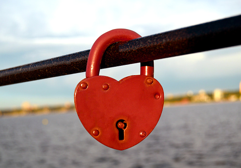 A heart-shaped lock on the chain above the lake on the bridge symbolizes a new family.