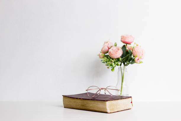 istock Book with pink roses over the white wall with natural light. 1424198546