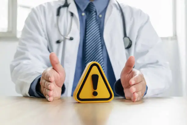 Warning symbol in hand of doctor.