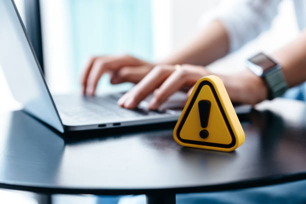 Warning sign placed on a table while businesswoman work. stock photo