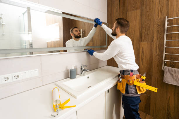 The worker installs the mirror in the bathroom. stock photo
