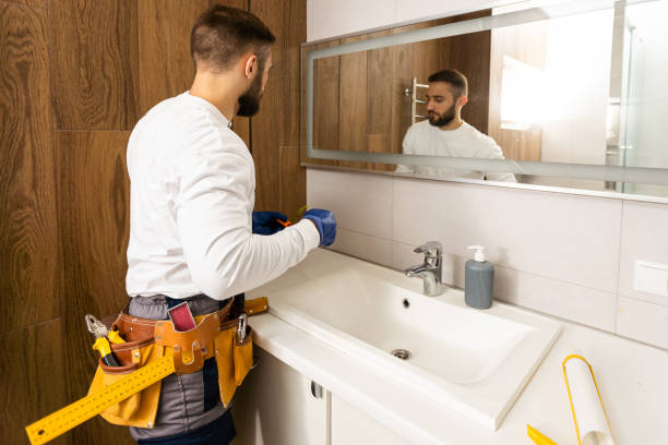 istock Man installing a mirror on wall in his renewed bathroom 1424202277