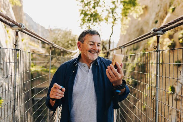 istock Happy senior man having a video call while hiking outdoors 1424207269