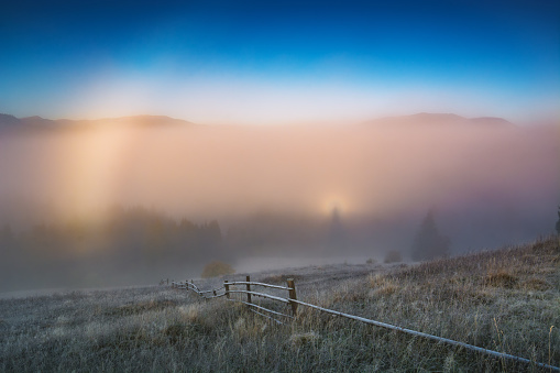 Deep morning fog in alpine valley. Broken ghost effect on a low clouds.