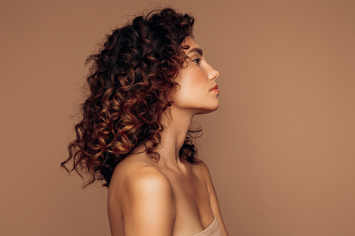 Portrait of beautifully looking young brown haired woman, dressed in a delicate evening makeup.Perfect model straightly gazing by kind, tender look at viewer. Beauty, elegance, hairstyling.