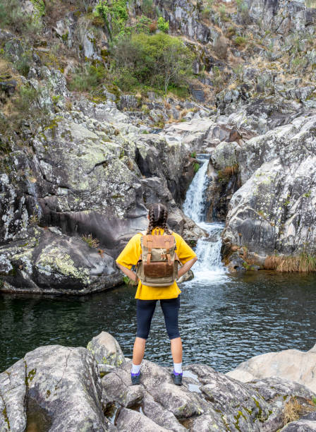istock Girl with arms on hips looking at a waterfall. 1424212674
