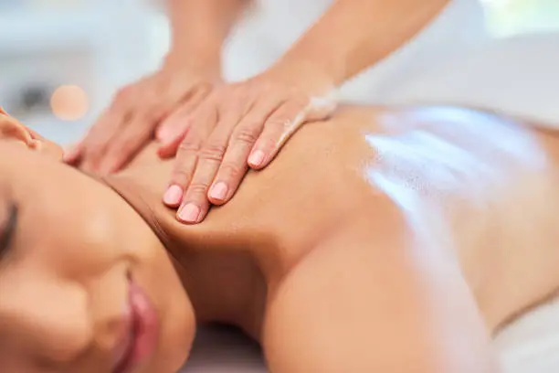 Luxury, wellness and zen spa massage on a young woman back, relaxing and stress free at a resort or center. Female enjoying healing treatment by a masseuse, pamper while massaging for muscle relief