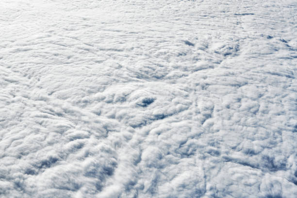 Breathtaking over clouds view from aircraft window, thick white blue clouds looks like soft foam, overcast with fresh frosty air. Beautiful cloudy sky view to troposphere, heavy cloudiness