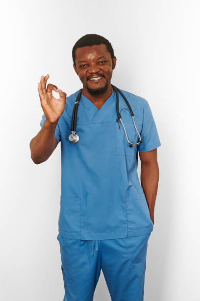 istock Smiling black surgeon doctor bearded man in blue coat with stethoscope makes OK gesture 1424214656