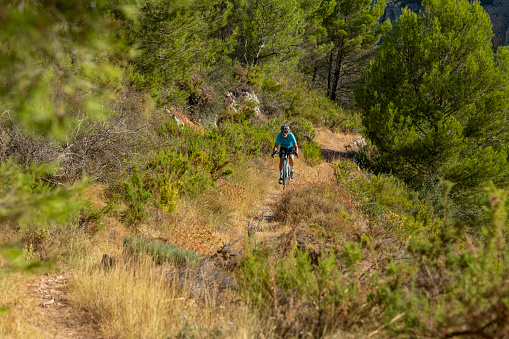 A male cyclist in a mediterranean forest gravel road bicycle ride in the Costa Blanca, Alicante, Spain