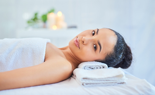 Beauty spa treatment for a woman to relax while lying on a massage bed or table ready for manual therapy. Portrait of a beautiful and attractive female in an aesthetic clinic