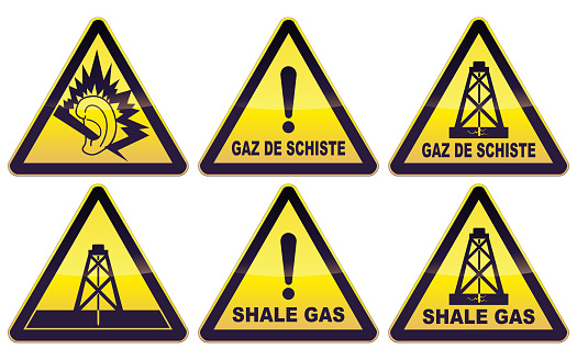 Collection of black and yellow triangular warning signs with, an ear in danger, an oil well or a drilling well with fracking and the wording shale gas in French and English