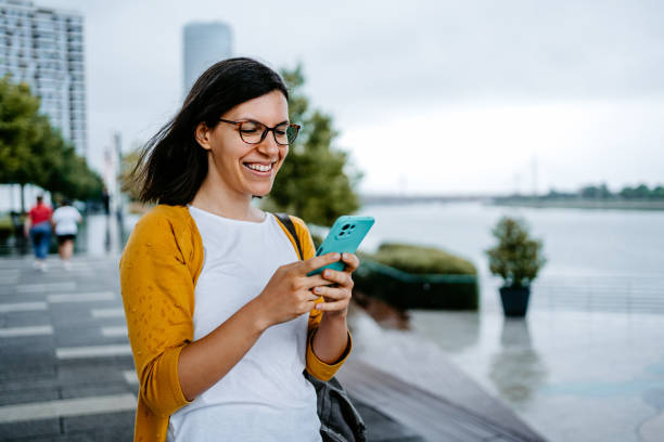 istock Young Woman Using Phone While Walking Down The Street 1424219835