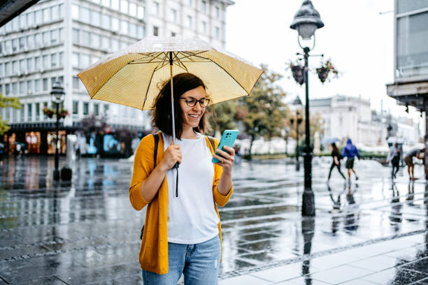 Young Woman Using Phone Outdoors On A Rainy Day