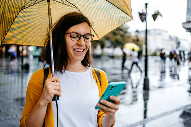 istock Young Woman Using Phone Outdoors On A Rainy Day 1424219951